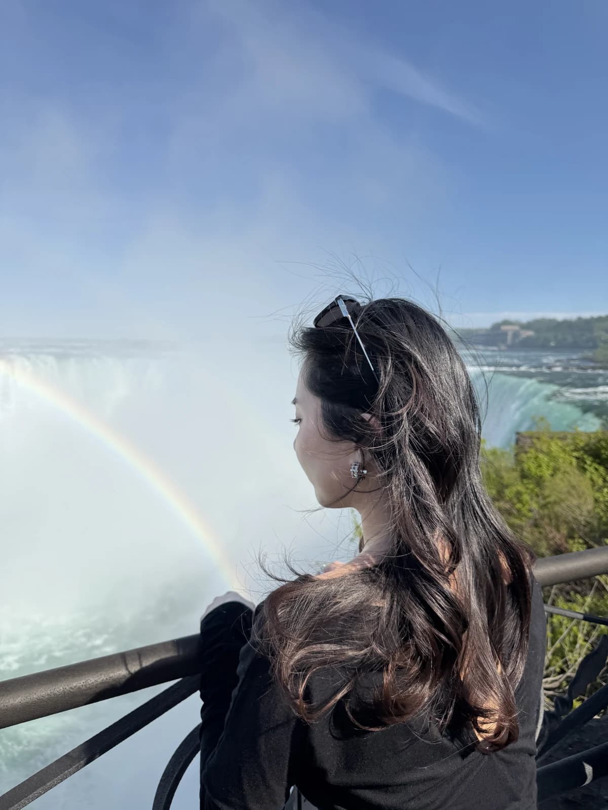 Melody beside a waterfall and rainbow beneath a blue sky