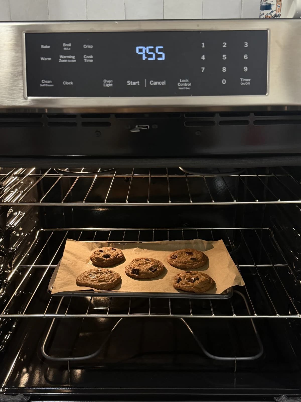 Chocolate chip cookies baking on a tray in a warmly lit oven