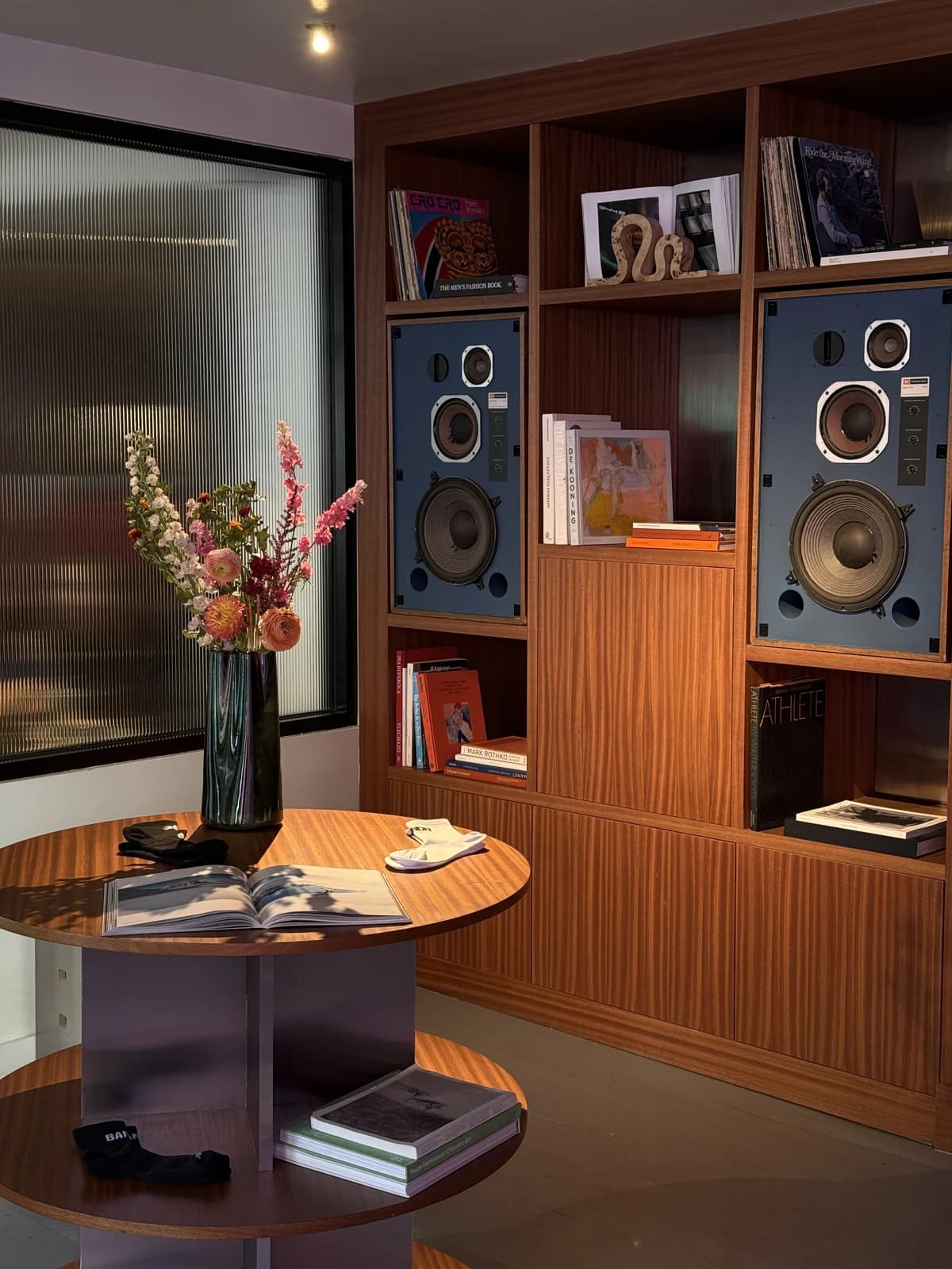 Blue speakers, records, flowers, and warm wooden shelves