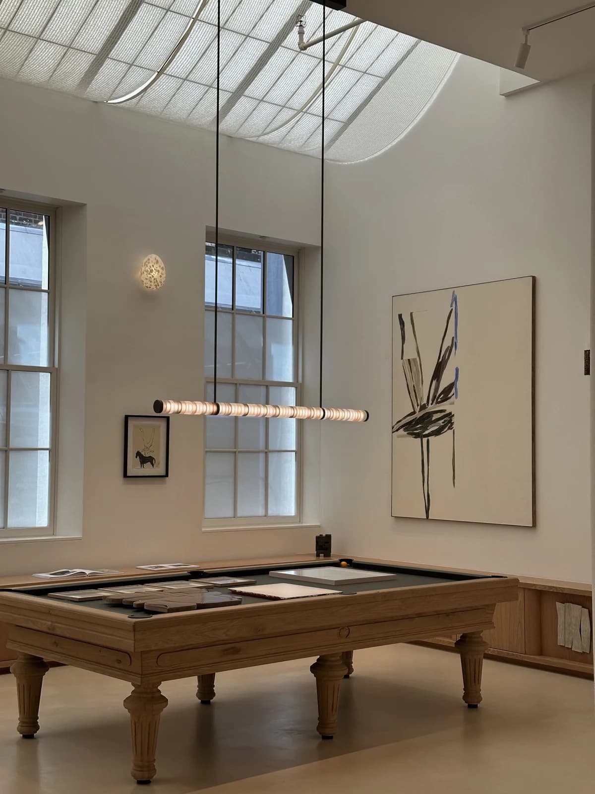 A warm neutral interior with a wooden pool table and pendant light